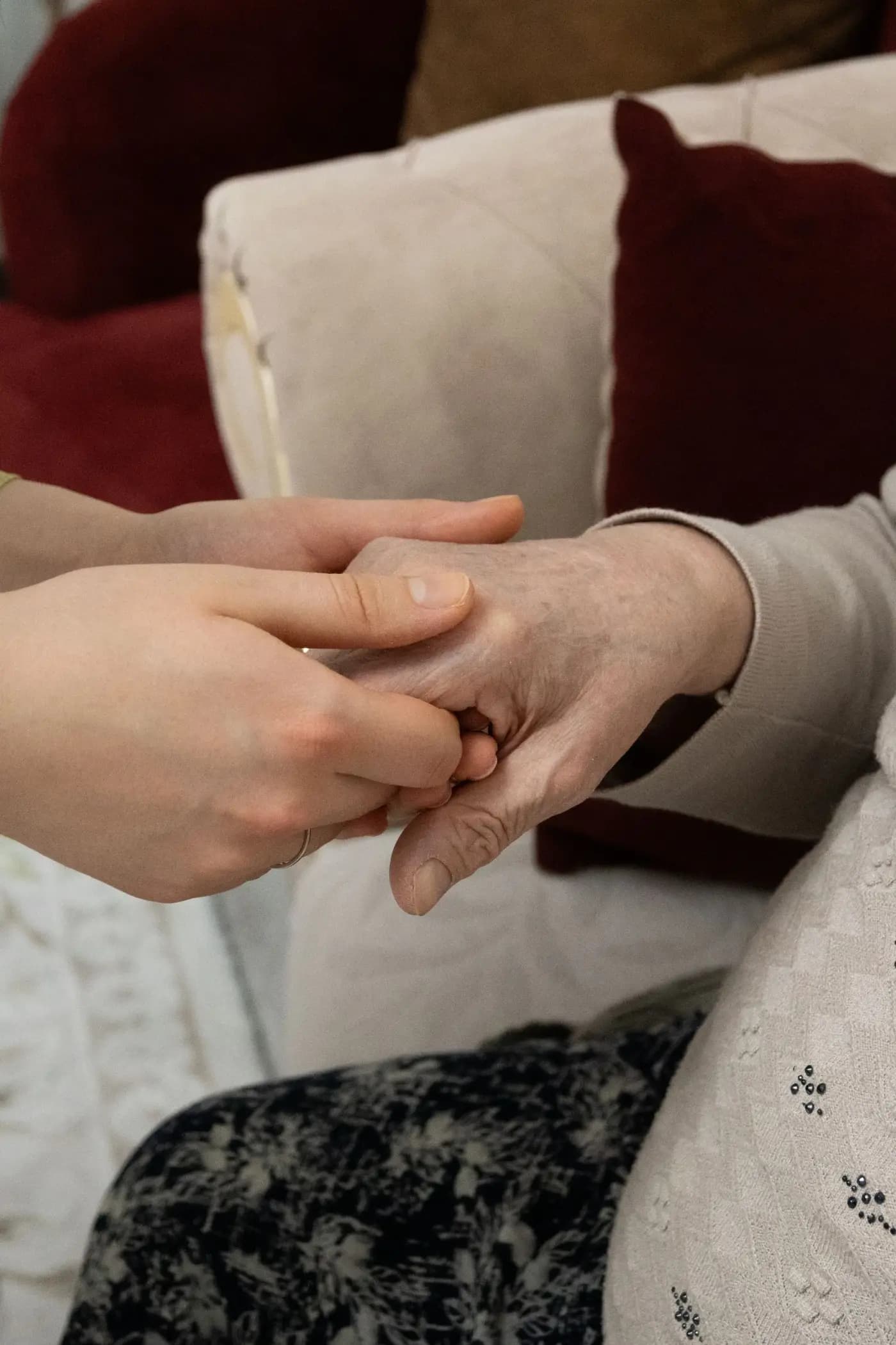 A younger pair of hands gently holding an older pair of hands