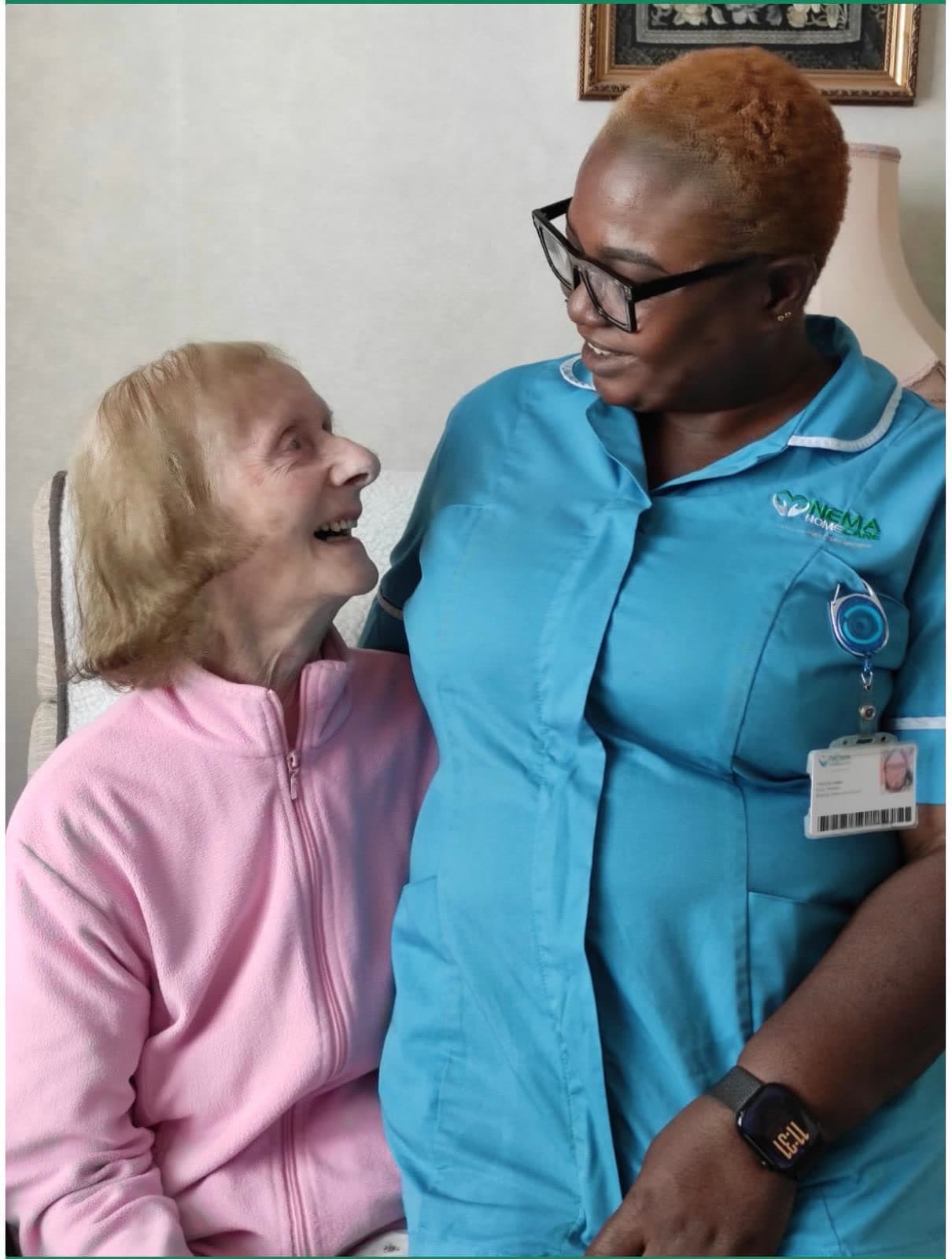 A Nema carer and an older woman smiling at each other at home