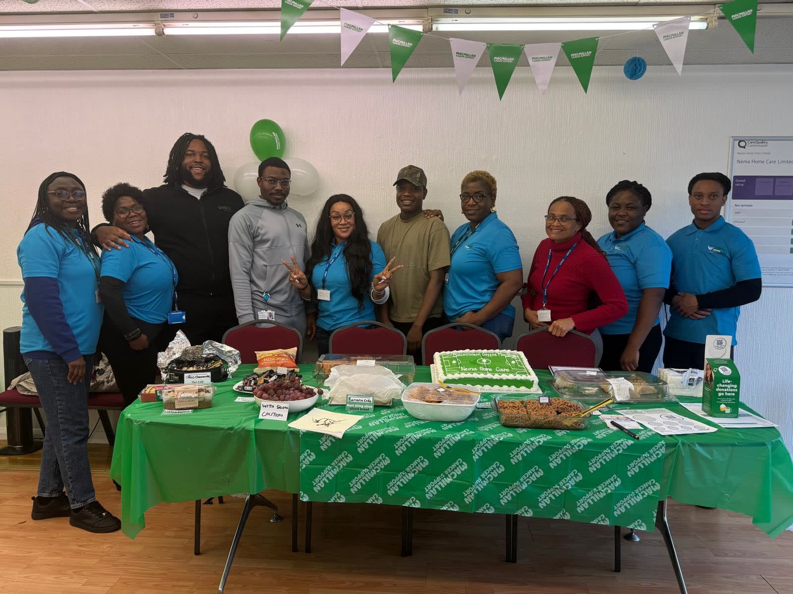 The Nema team in matching blue tops behind a table of cakes and food